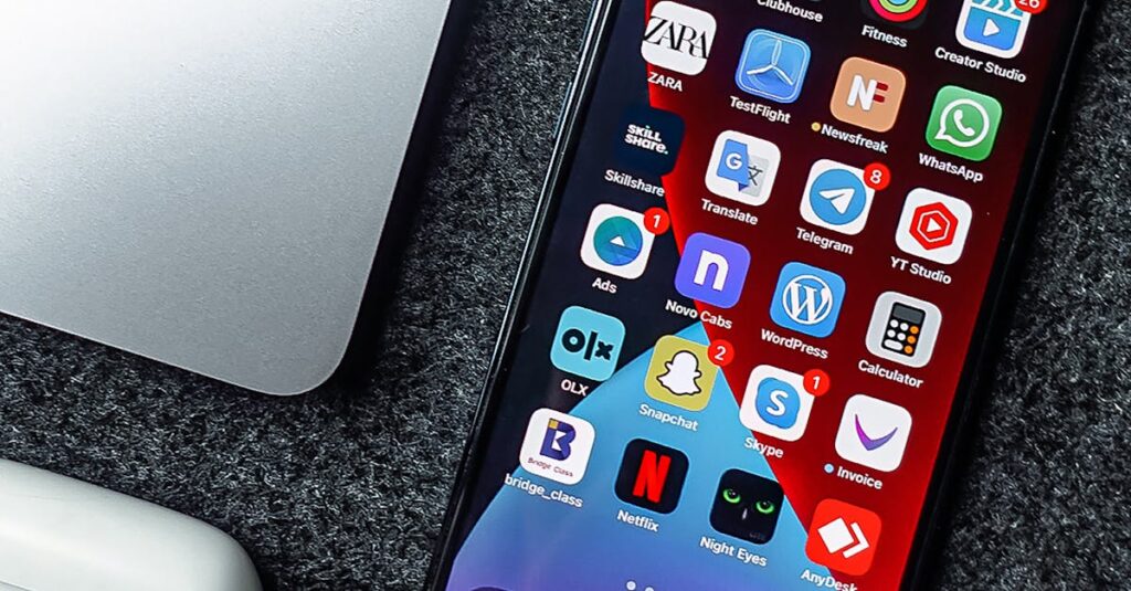 Flat lay of a smartphone, laptop, and earphones on a grey surface. Perfect for tech and gadget themes.